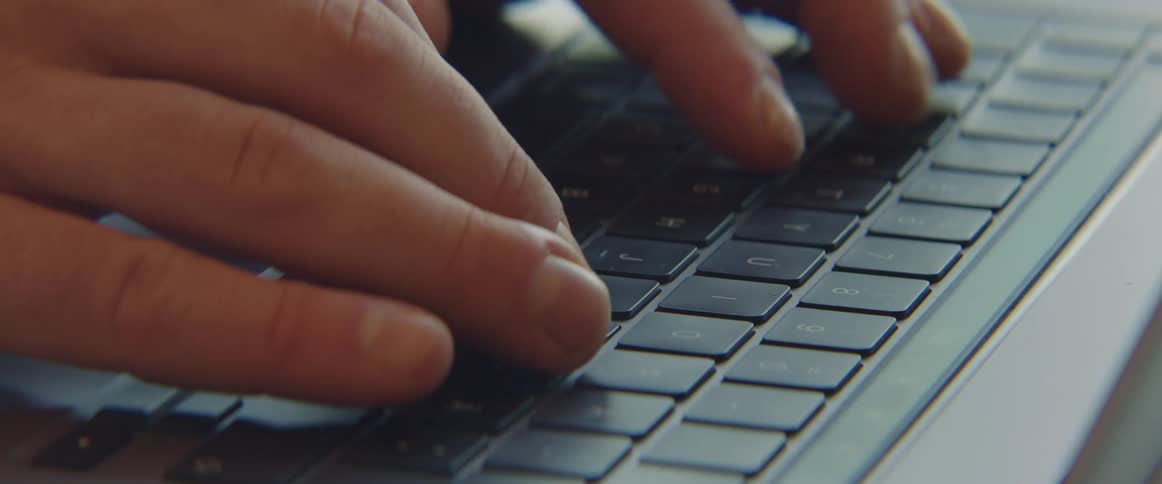 Fingers are typing on a laptop computer keyboard