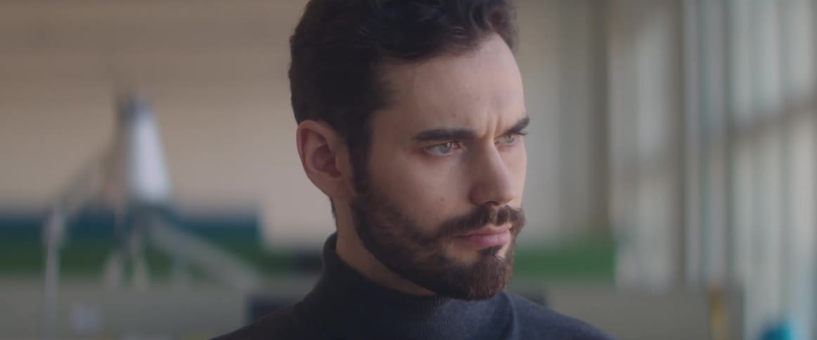 Young bearded man sits on a desk at the office and starts working