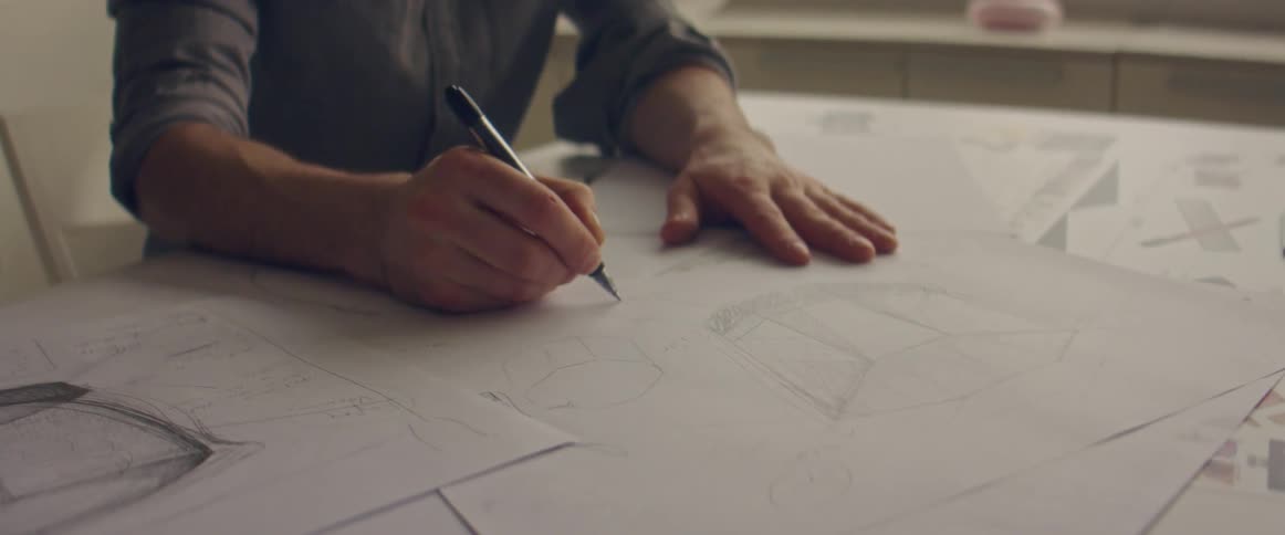 Man drawing a design un paper using a mechanical pencil