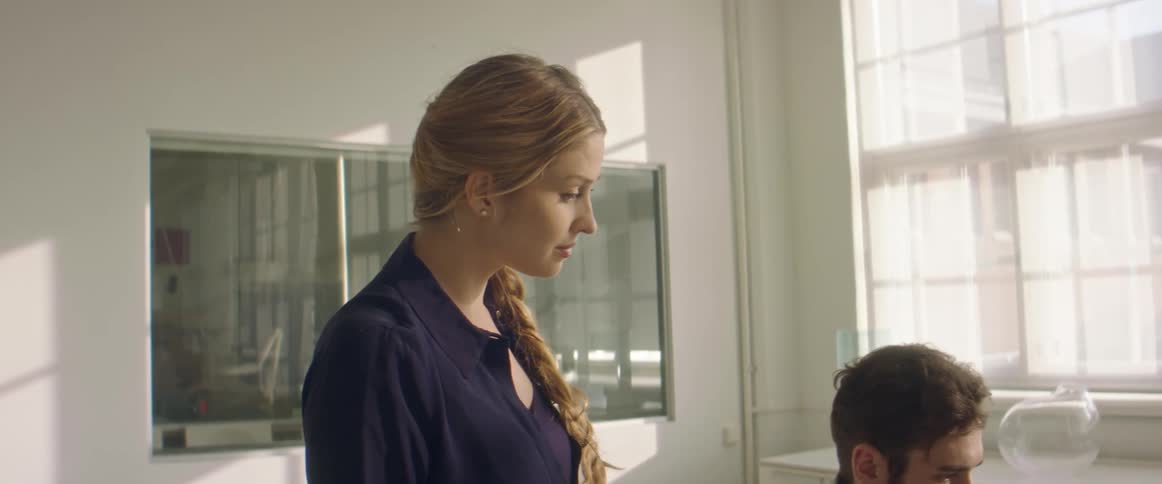 Woman stands while holding discussion with sitting coworker in white decorated room