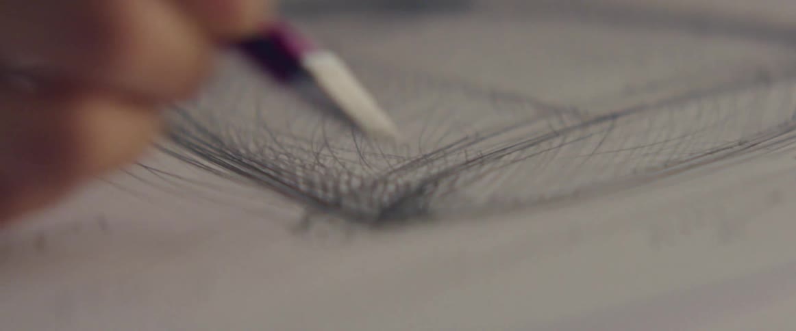 A person in a room drawing on a paper with a pen