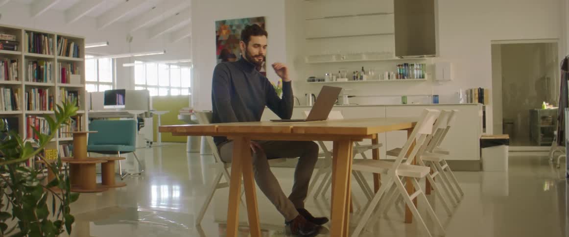 Man working at the office talking on a video call through a laptop