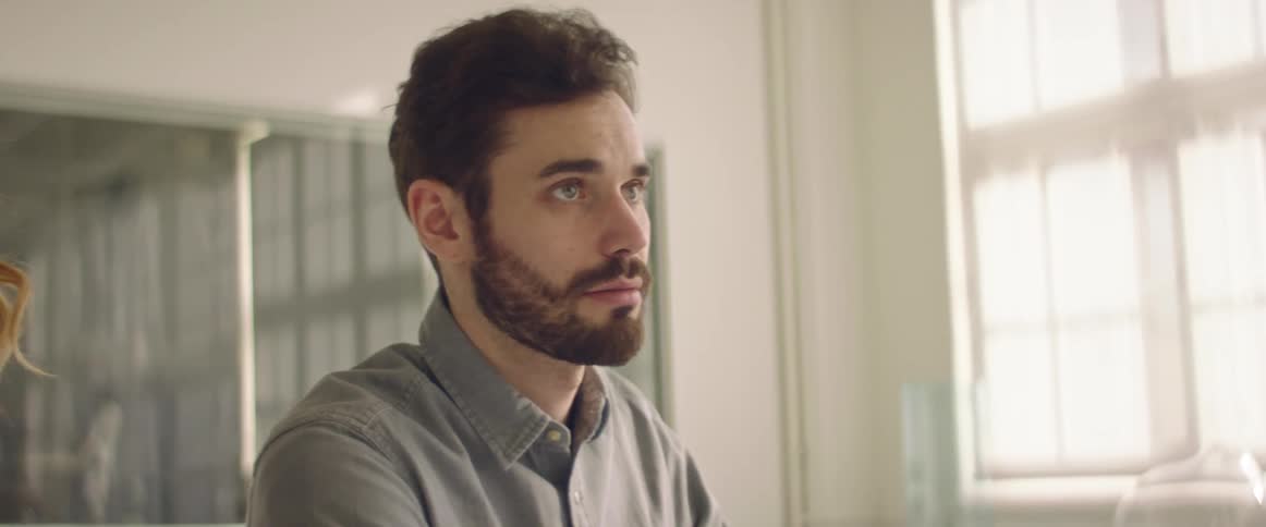 Man working in the office in front of a laptop talking to his boss