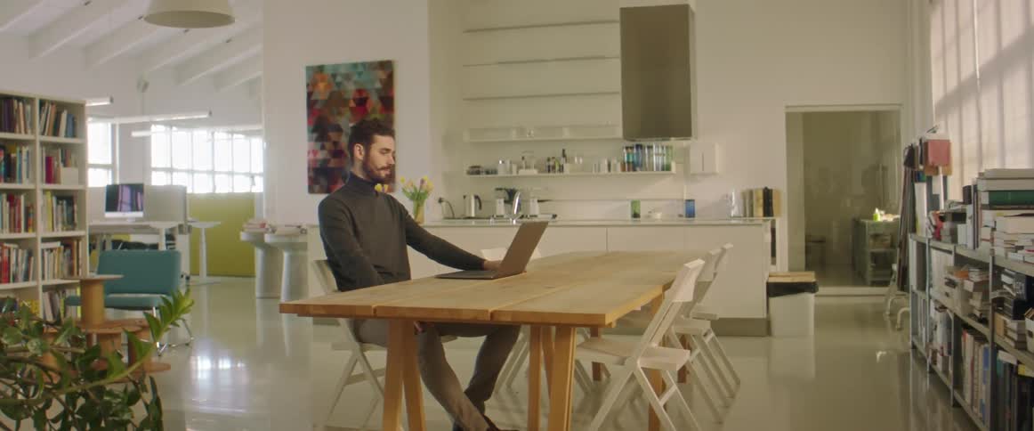 A man sitting in a room using a laptop to talk to someone
