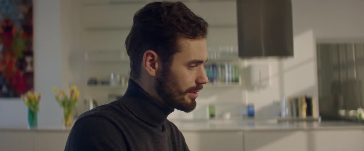 Bearded man talks while in front of a counter with yellow flowers
