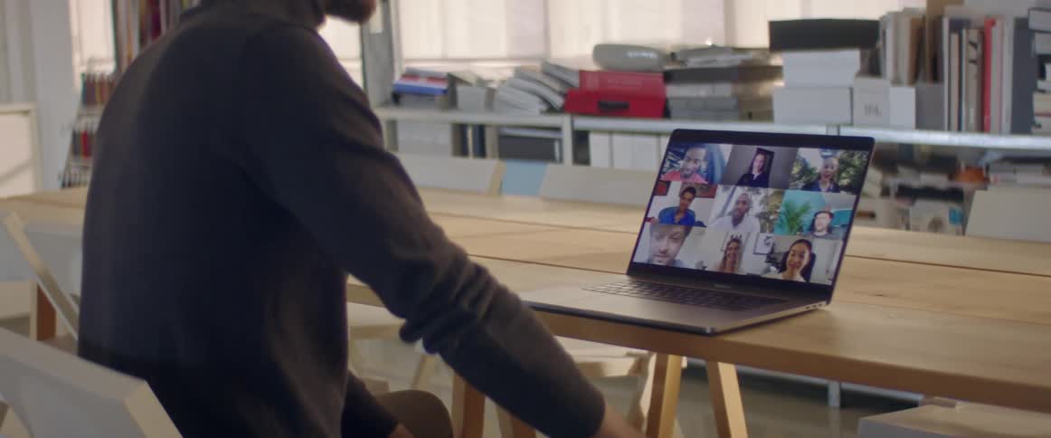 A man in a room sitting on a chair looking at a laptop on a table