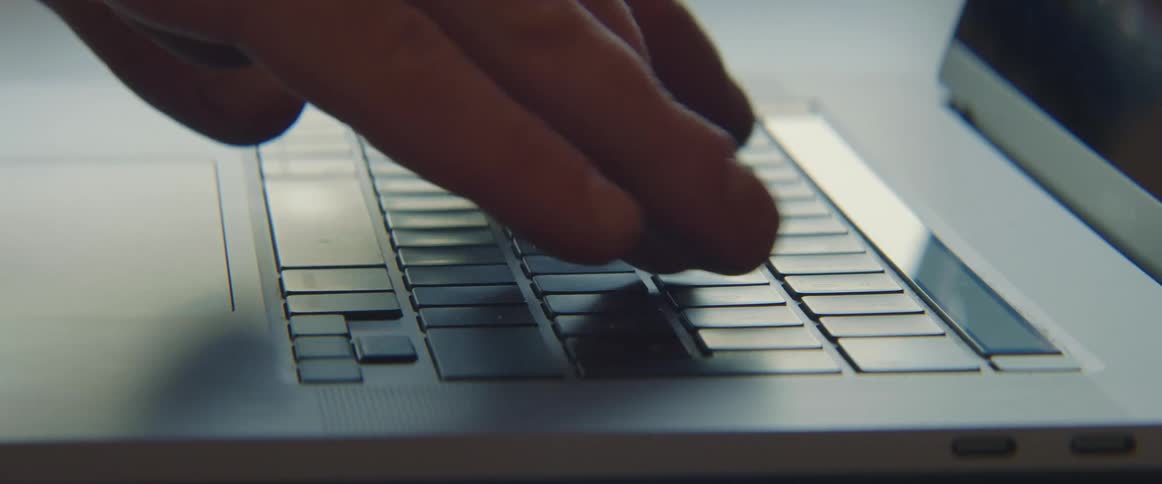 A person typing on a keyboard on a laptop