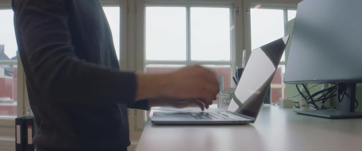 Young man places a laptop over a desk at the office and starts working