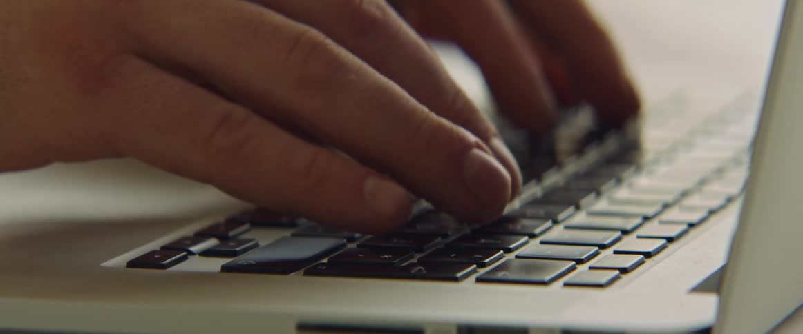 Fingers are typing on a laptop computer keyboard