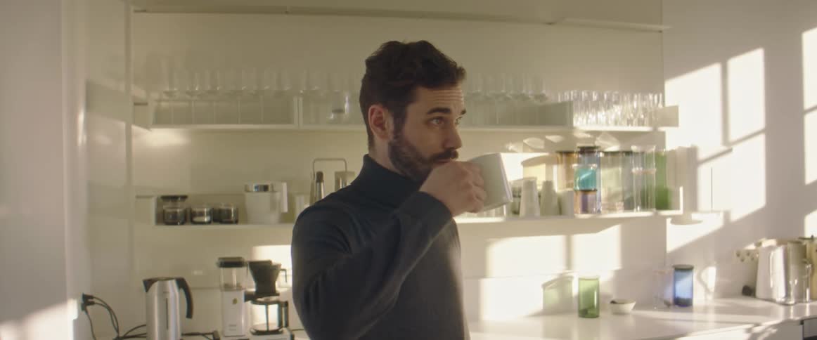 A man pours a cup of coffee and then drinks from the mug