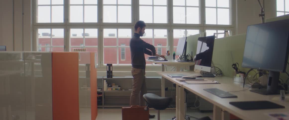 Man carrying a briefcase enters the office and starts working
