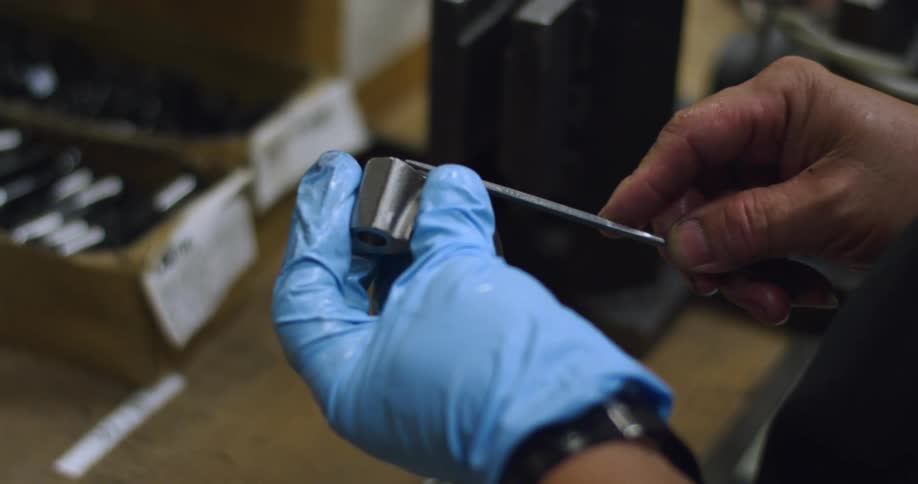 A person filing a piece of metal over a workbench