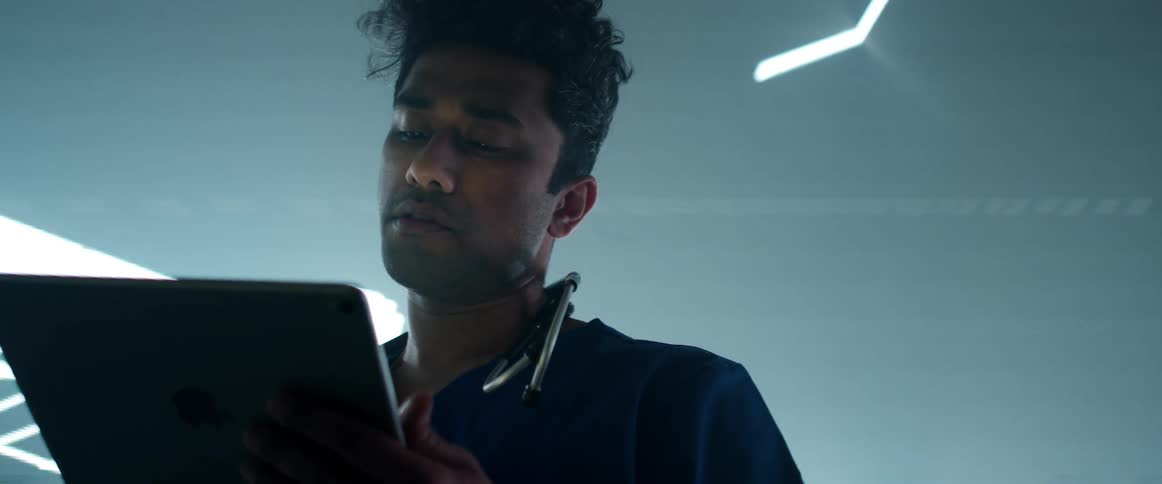 A man in a room with a stethoscope and a tablet with a screen in the background