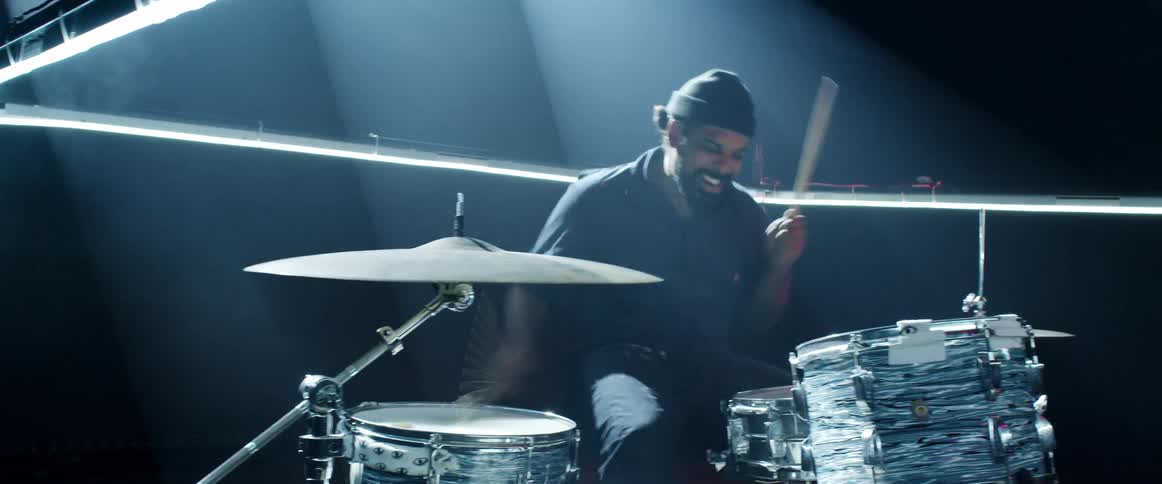 Man playing a the drums surrounded by lights