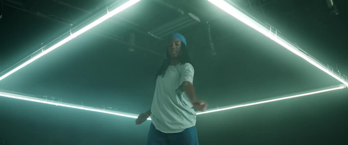 A woman with a bandanna and earrings dancing in a room