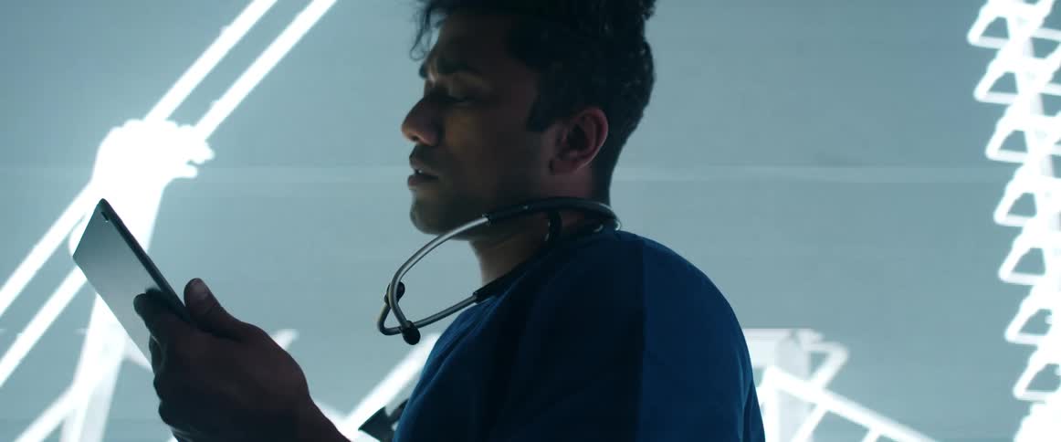 A man in a room with a stethoscope and a tablet with a screen in the background