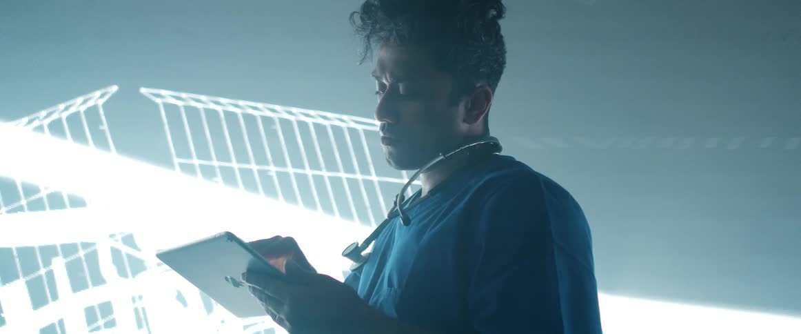 Man standing in front of a giant digital display using a tablet