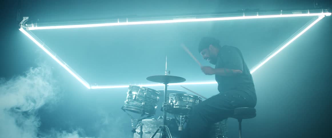 Drummer performs on stage under blue neon in foggy club