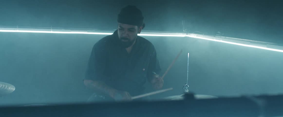 A man smiles as he plays the drums