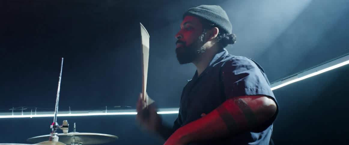 A man is playing the drums with smoke all around