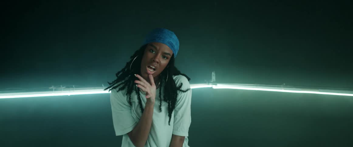 A woman with a bandanna and earrings dancing in a room