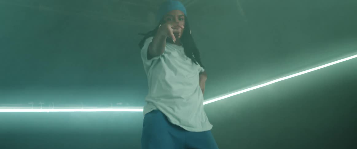 Woman dances points in darkened room lit by long neon lights