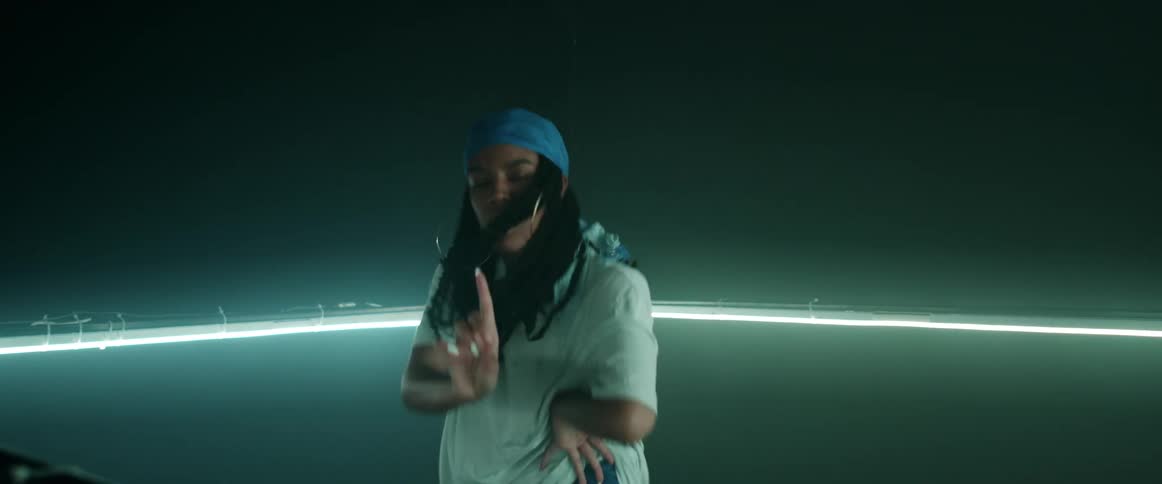 Young woman energetically dancing inside a ring of green lights inside a dark room