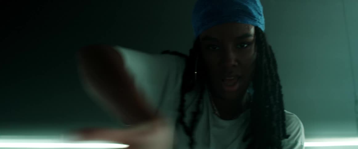 Woman with a headband braids and a white t shirt dances in a dark room