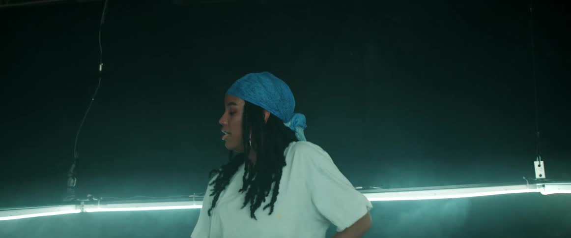 Young woman energetically dancing inside a ring of green lights inside a dark room