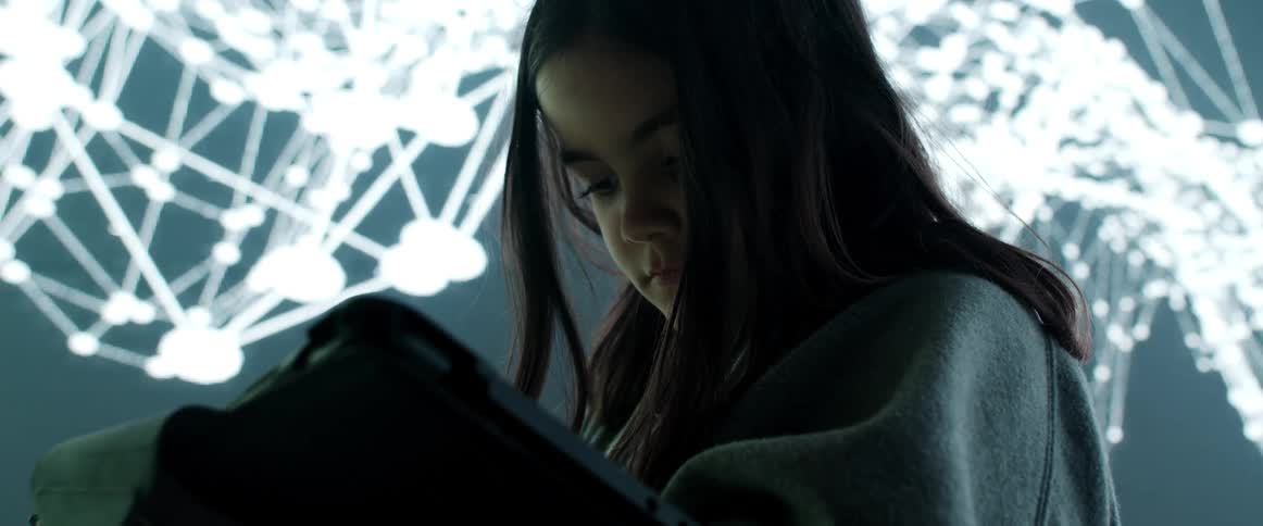 A girl using a tablet in a room with a large screen