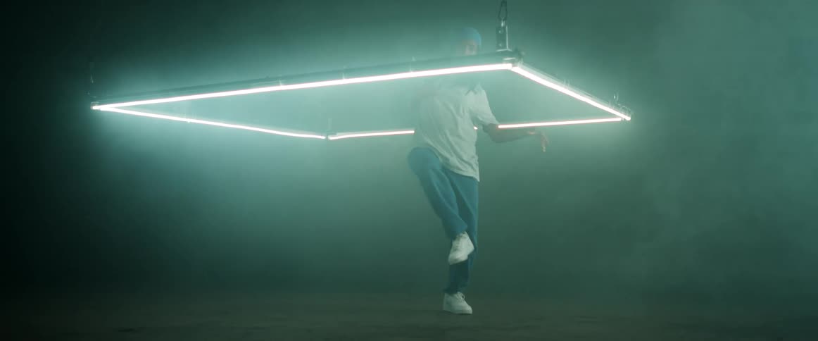 A teenage girl dances in a square of bright lights