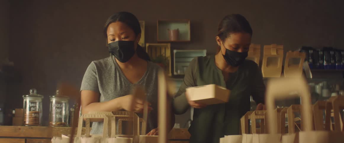 Women wearing black face masks working on a shop preparing an order