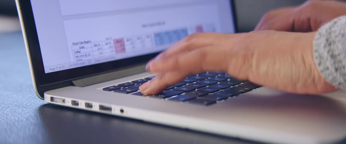 Woman types on laptop entering data into forms