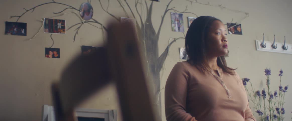 A woman in a room using a smart phone with a chair in the foreground and a wall in the background