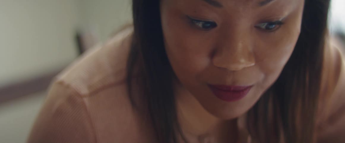 Woman with a straight hair and a blouse talks to someone