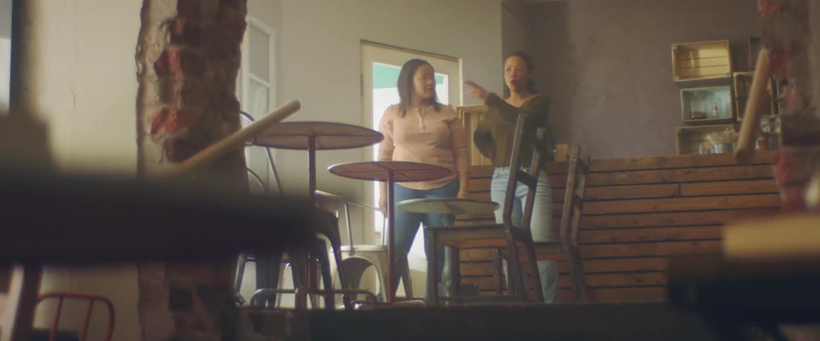 Two women discuss furniture placement in shop
