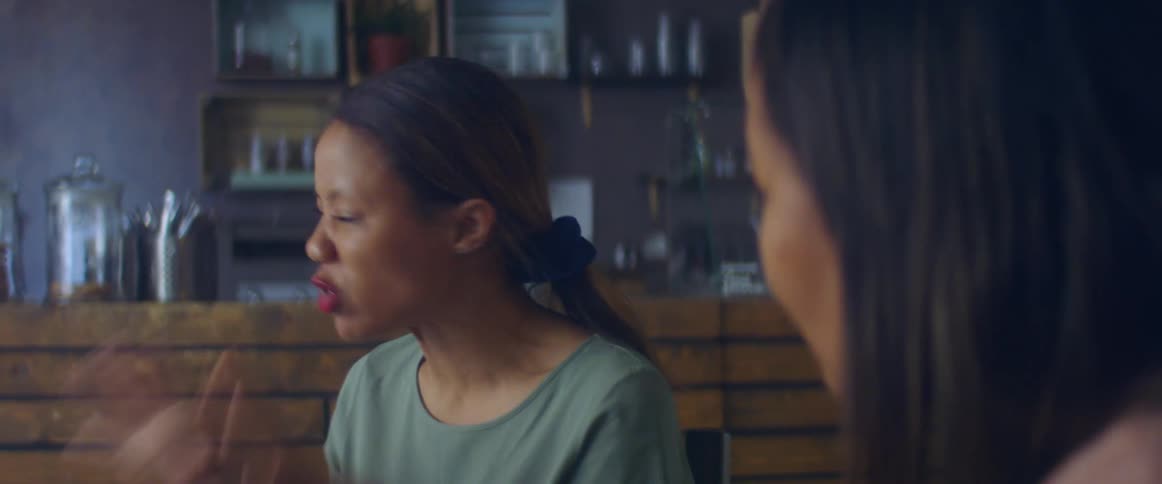 Two women in a room talking with a wall with shelves and containers in the background