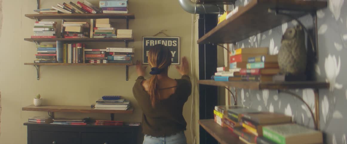 Woman hangs sign on wall before adjusting contents of shelves