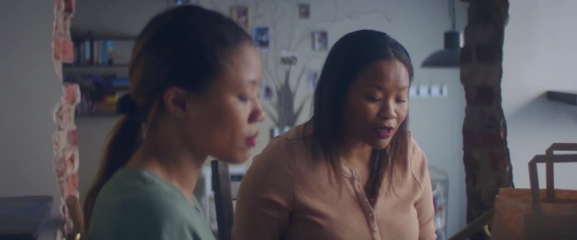 Woman with a straight hair and a brown shirt consoles woman wearing a light blue shirt after fighting in a cafe shop