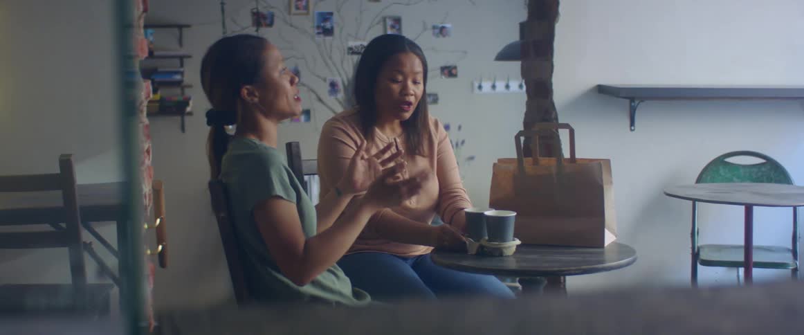 Two friends are talking together and sitting at a table