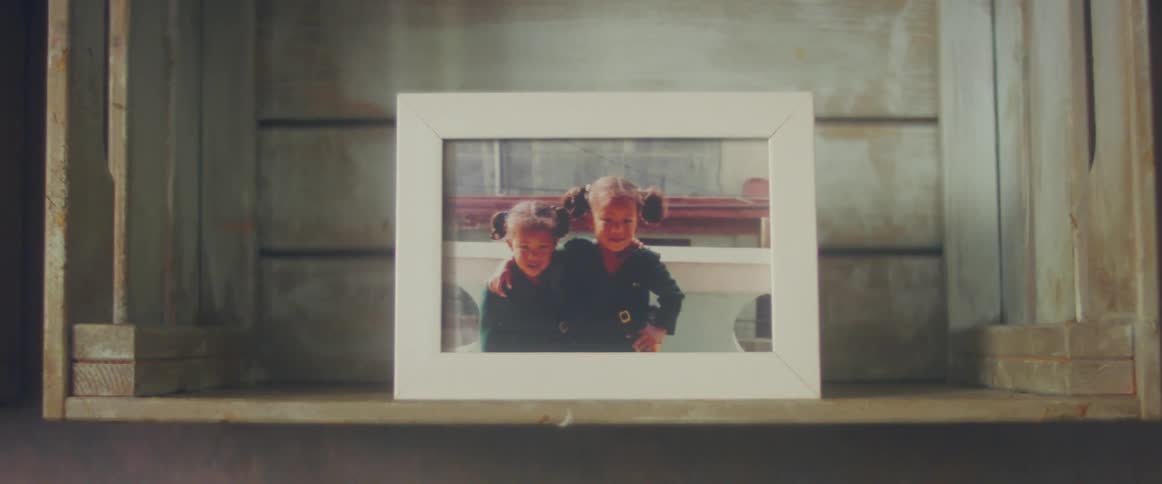 A picture frame of children is on a bookshelf