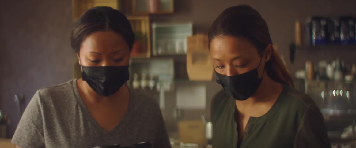 Women wearing black face masks working on a shop preparing an order