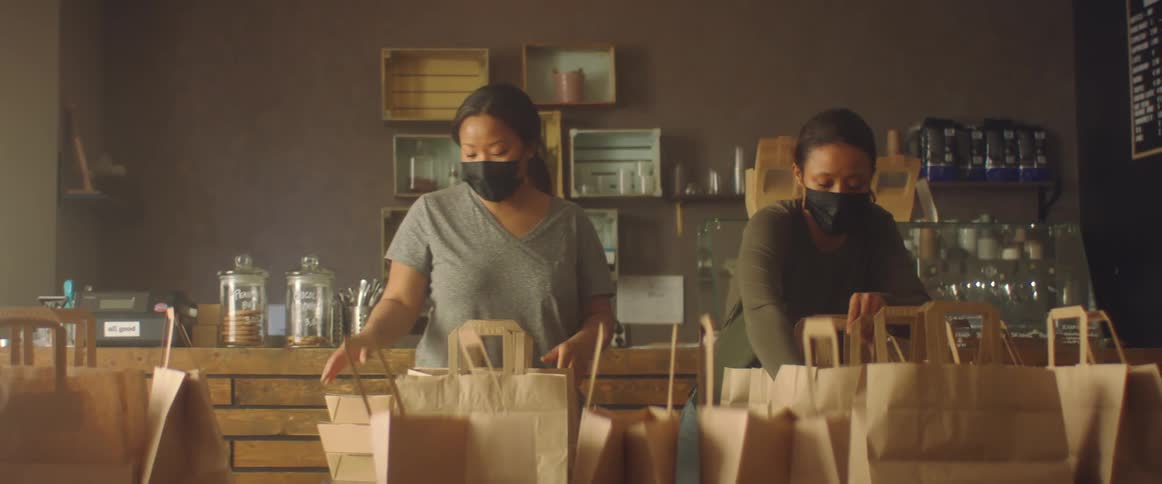 Women wearing black face masks working on a shop preparing an order
