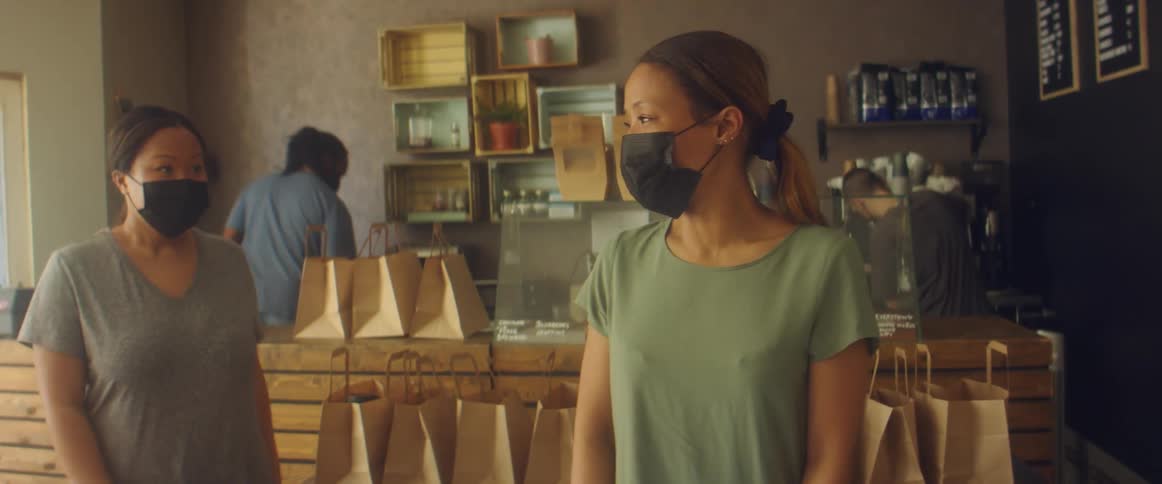 Women wearing black face masks working on a shop preparing an order