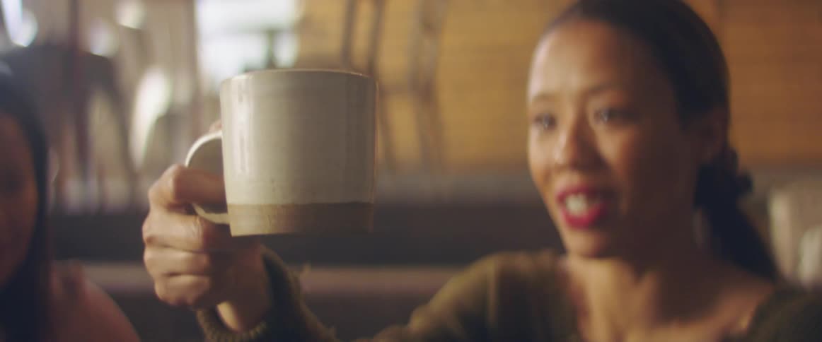 A woman is sitting and holding a coffee cup