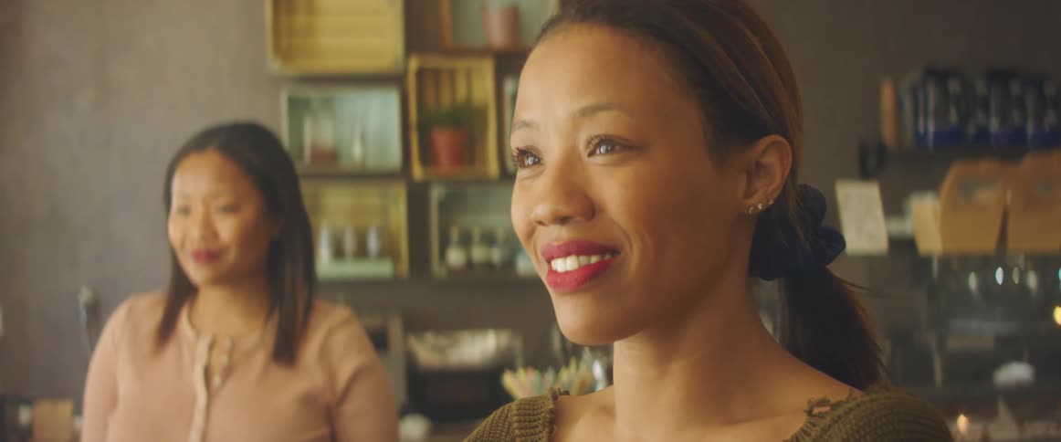 Two women stand in a store looking happy