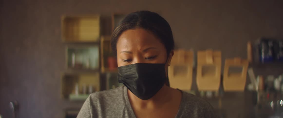 An employee in a store with a mask nods her head