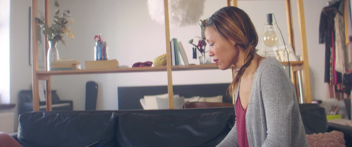 A woman sits on her couch and types on her laptop that is open next to her
