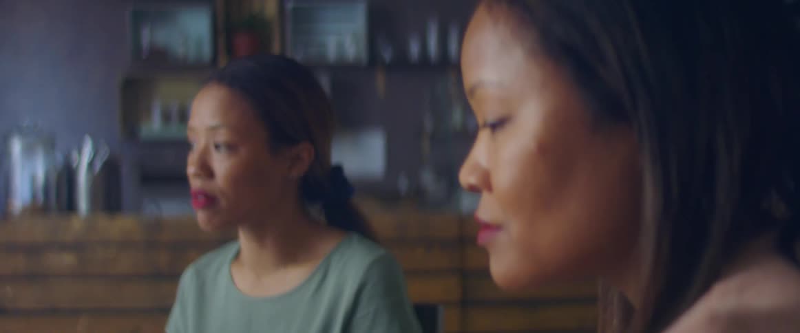 Two women sit at shop near counter having heated discussion