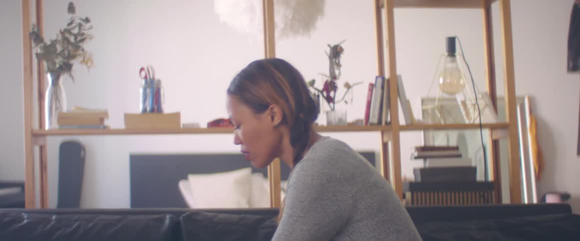 A woman is in a room and sitting on a couch